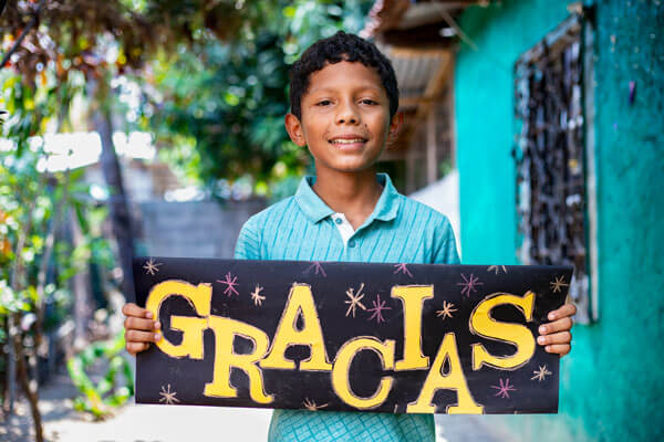 Un enfant tenant une pancarte sur laquelle est écrit "Gracias" (merci)