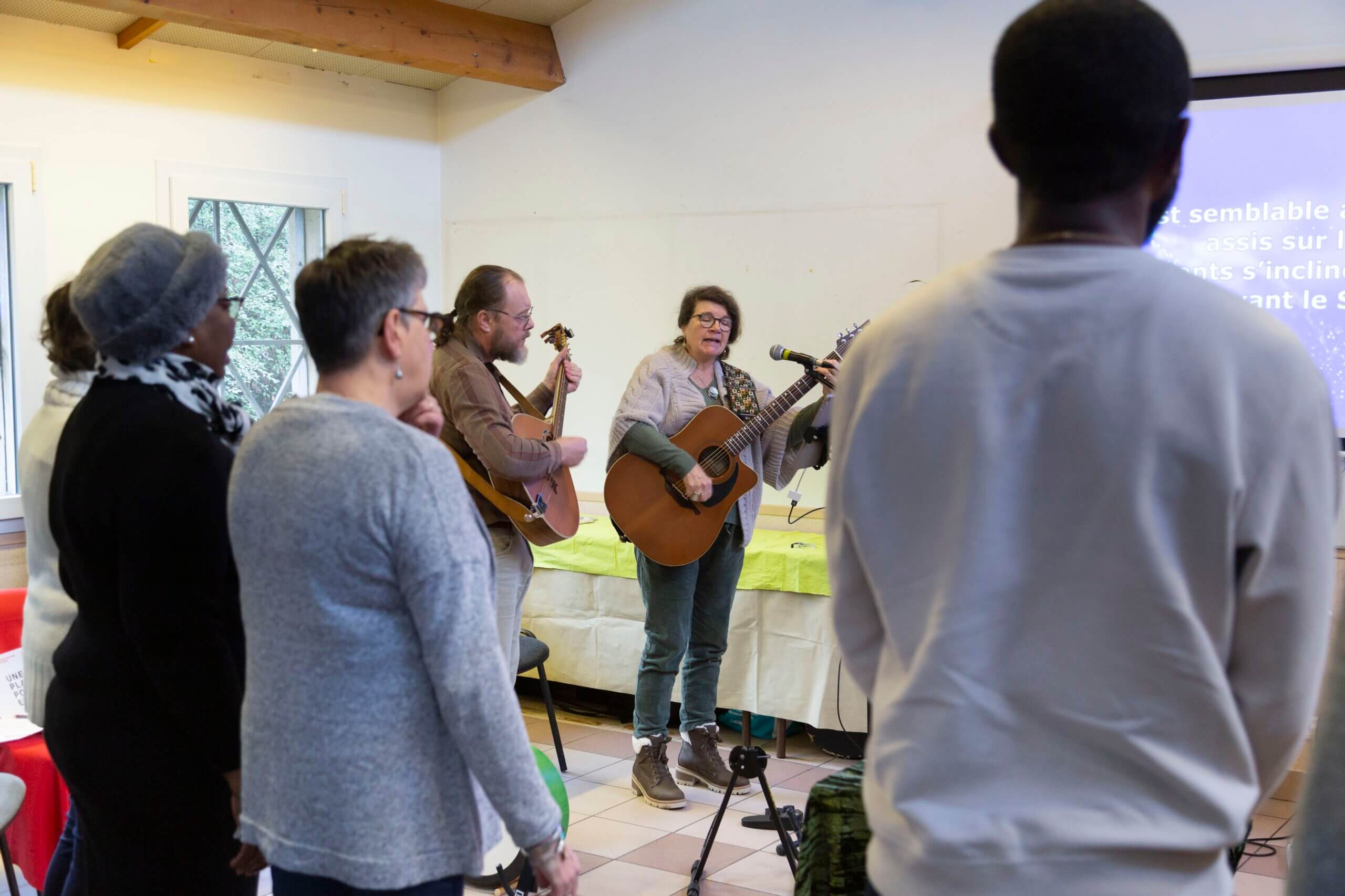 Des gens debout en train de chanter avec deux guitaristes à l'arrière plan
