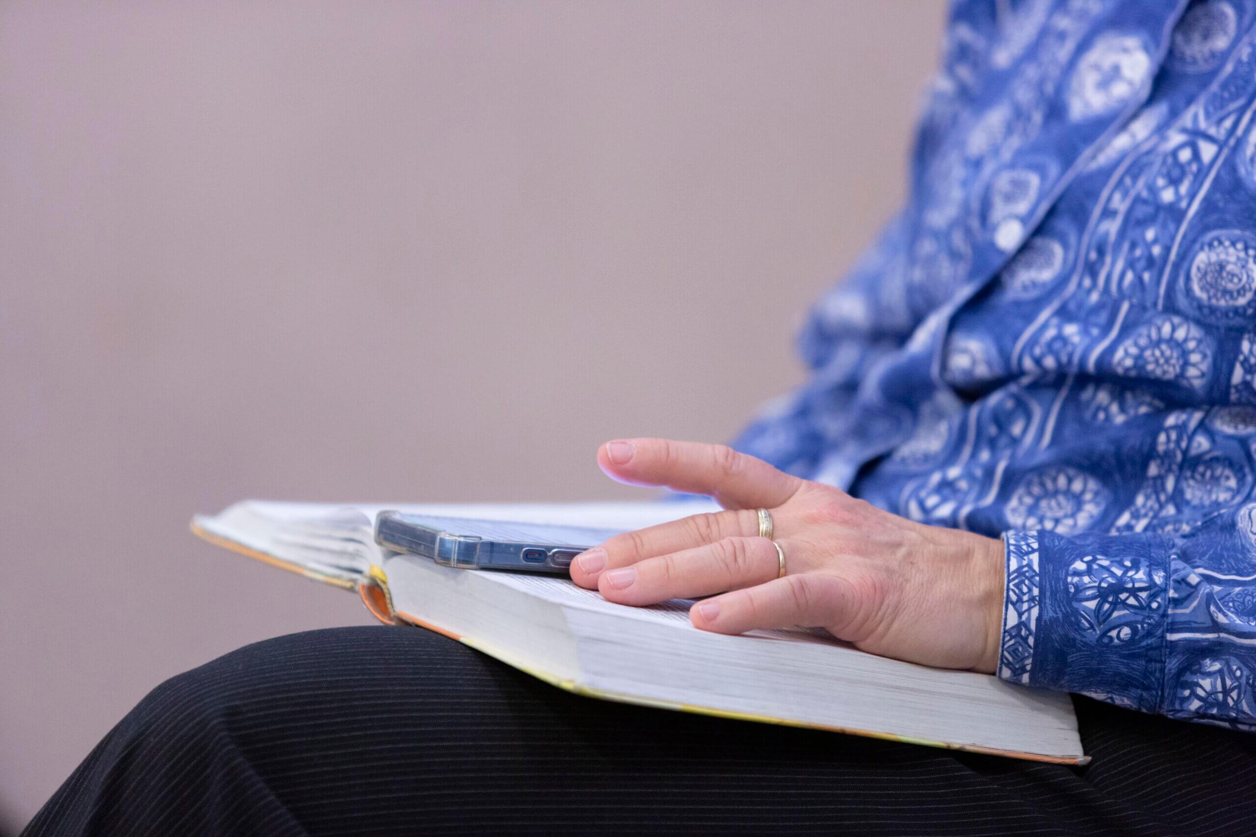 Les mains d'une femme lisant une Bible posée sur ses genoux
